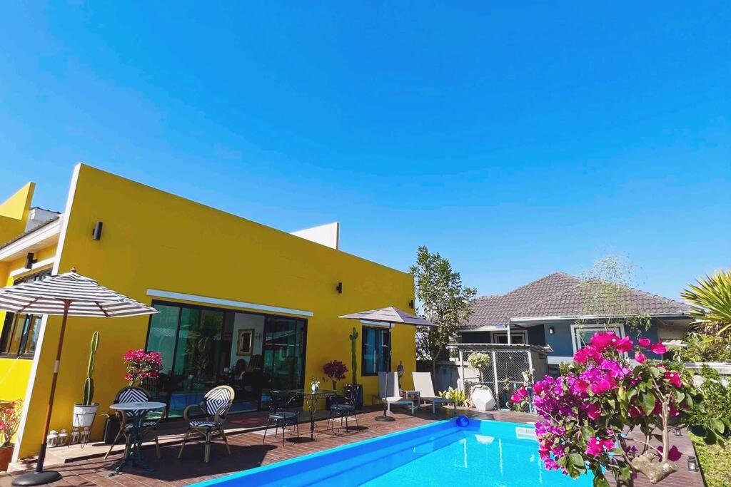 清莱Colorful Pool Villa, Chiang Rai, Thailand的黄色的房子,前面有一个游泳池