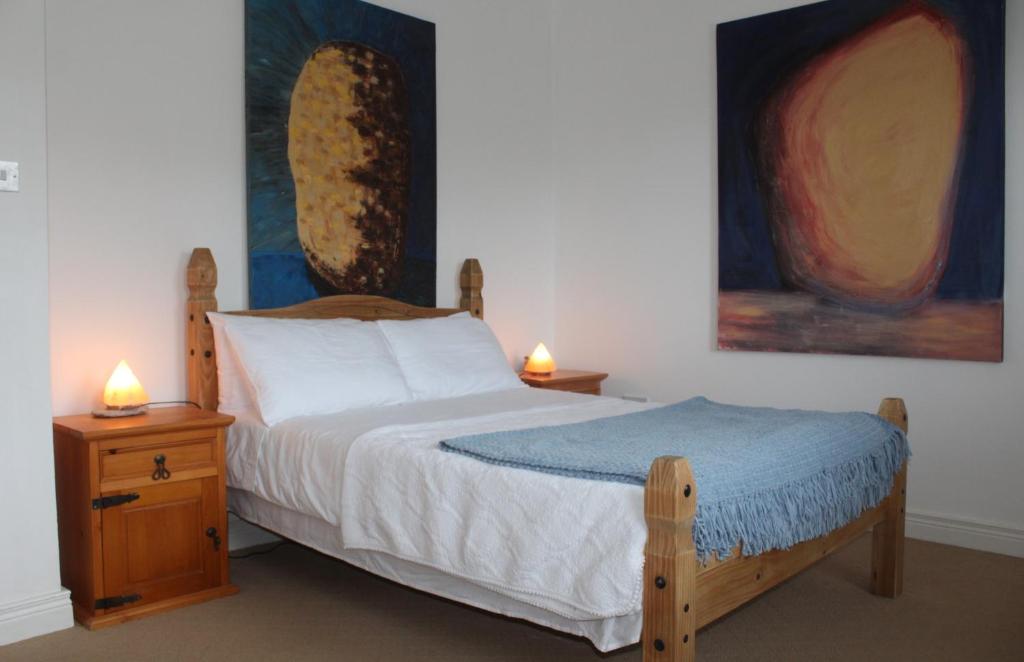 Malin HeadMalin Head SolasTobann ArtHouse Room 1 En-suite的一间卧室配有一张木床、两个床头柜和两个灯。