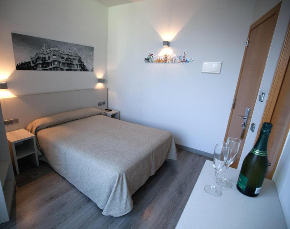 圣阿德里安-德贝索斯圣阿德里雅辞屋塔酒店的一间小卧室,配有一张床和一瓶葡萄酒