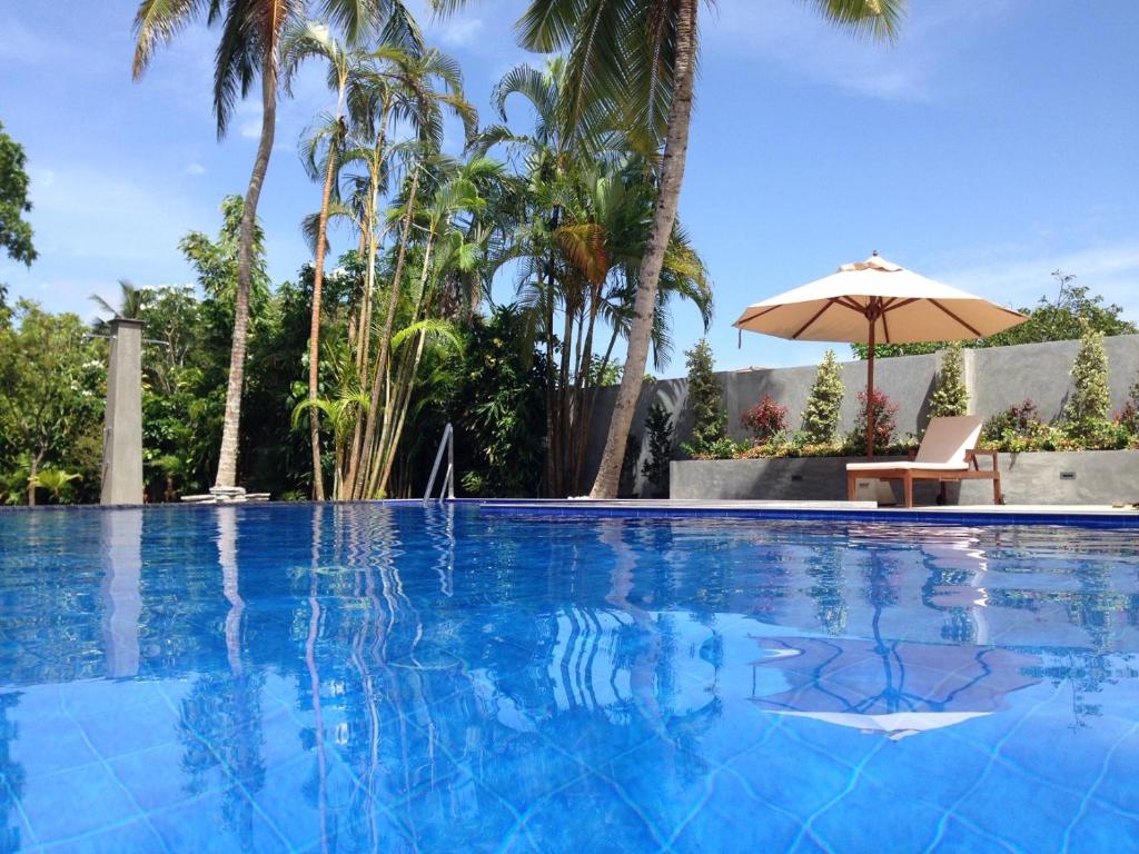 希克杜沃TROPICAL HOUSE - Jungleside Villa的一个带椅子和遮阳伞的游泳池