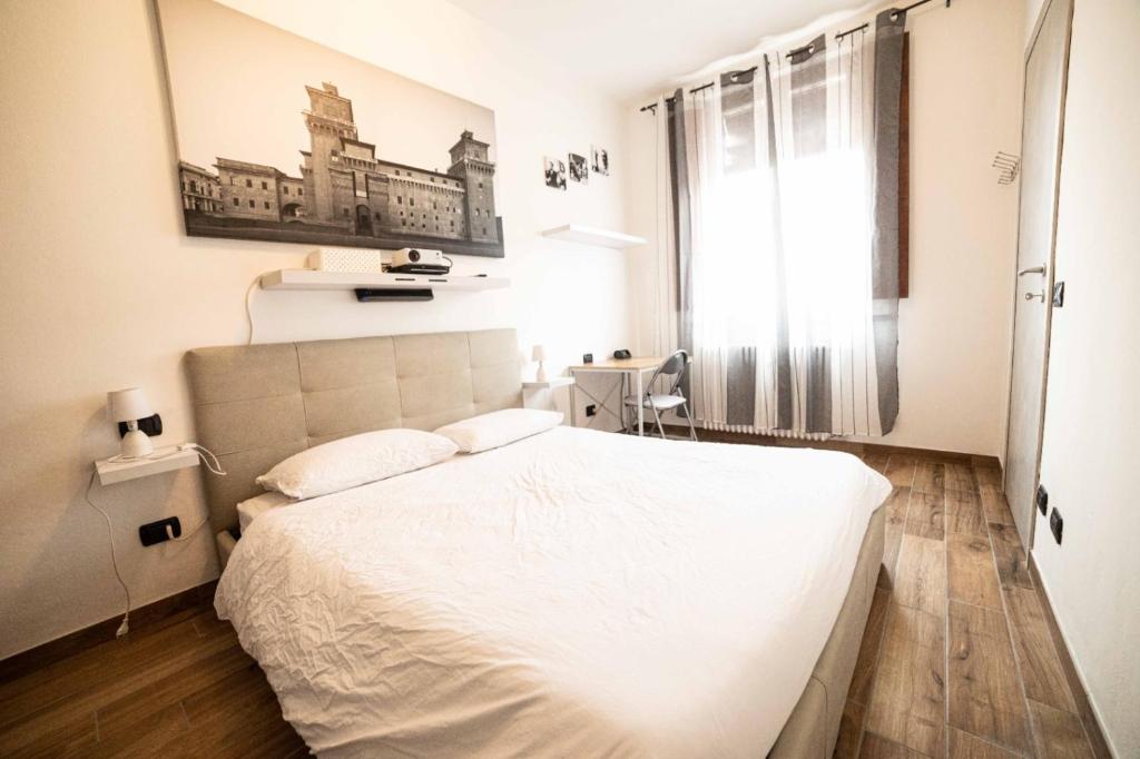费拉拉La dolce vita的卧室配有白色的床和窗户。