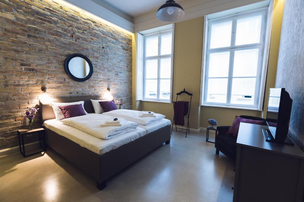 布达佩斯遗产之家公寓酒店的一间卧室设有一张床和砖墙