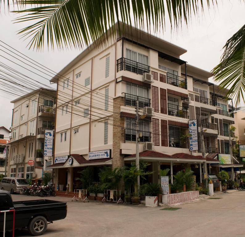 芭堤雅市中心Bluebird Inn Pattaya的街道上一座大型公寓楼,设有停车场