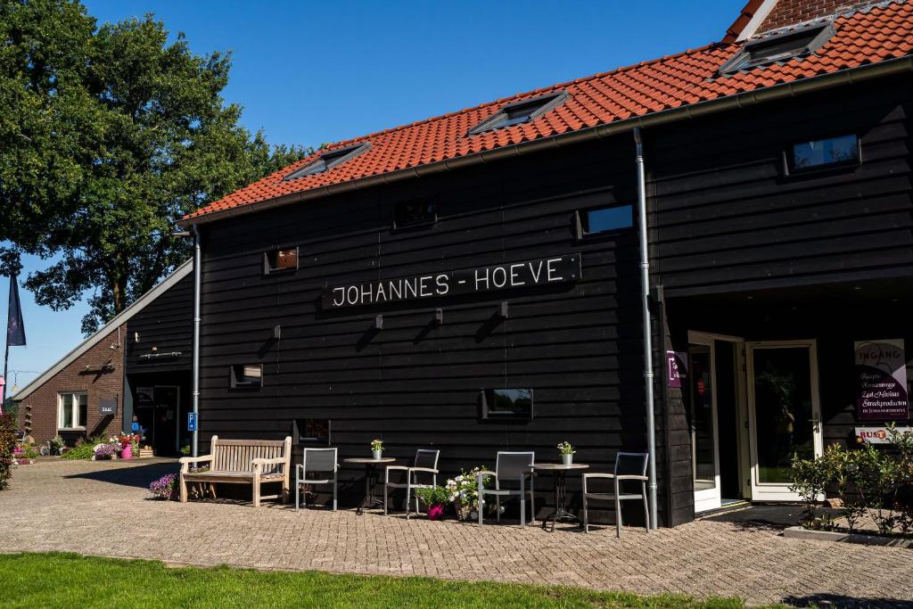 Westerhaar-VriezenveensewijkDe Johanneshoeve的一座黑色建筑,前面设有桌椅