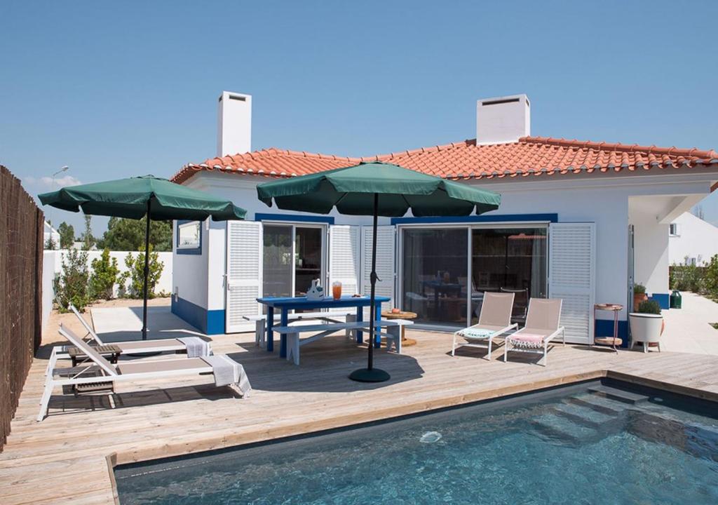 孔波尔塔Villa Nova的一个带桌子和遮阳伞的庭院和一个游泳池