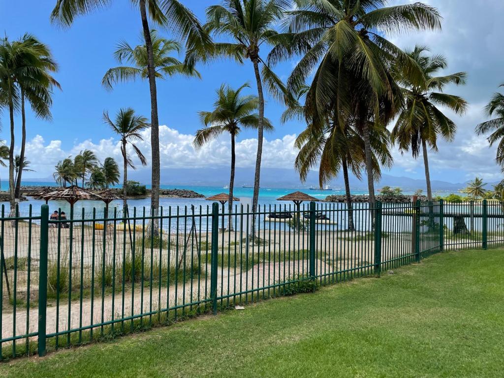 哥西尔Cauris Lodge du Marisol vue mer accès direct plage的棕榈树海滩前的围栏