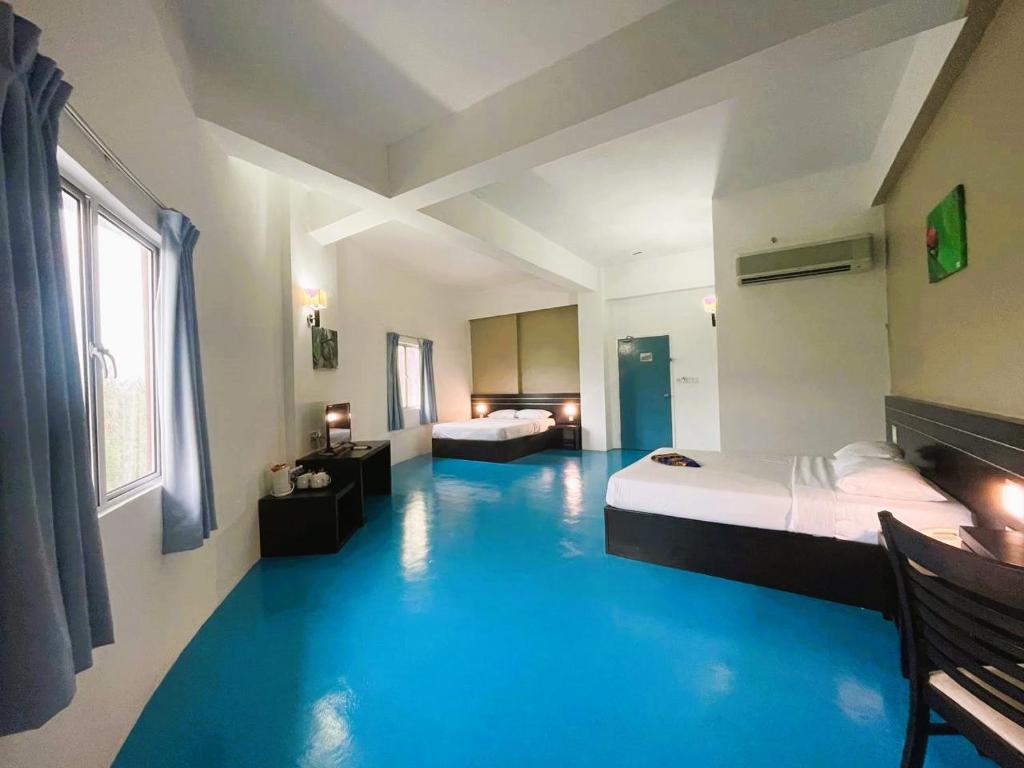 珍南海滩Kuala Melaka Inn的一间设有两张床的客房,铺有蓝色的地板