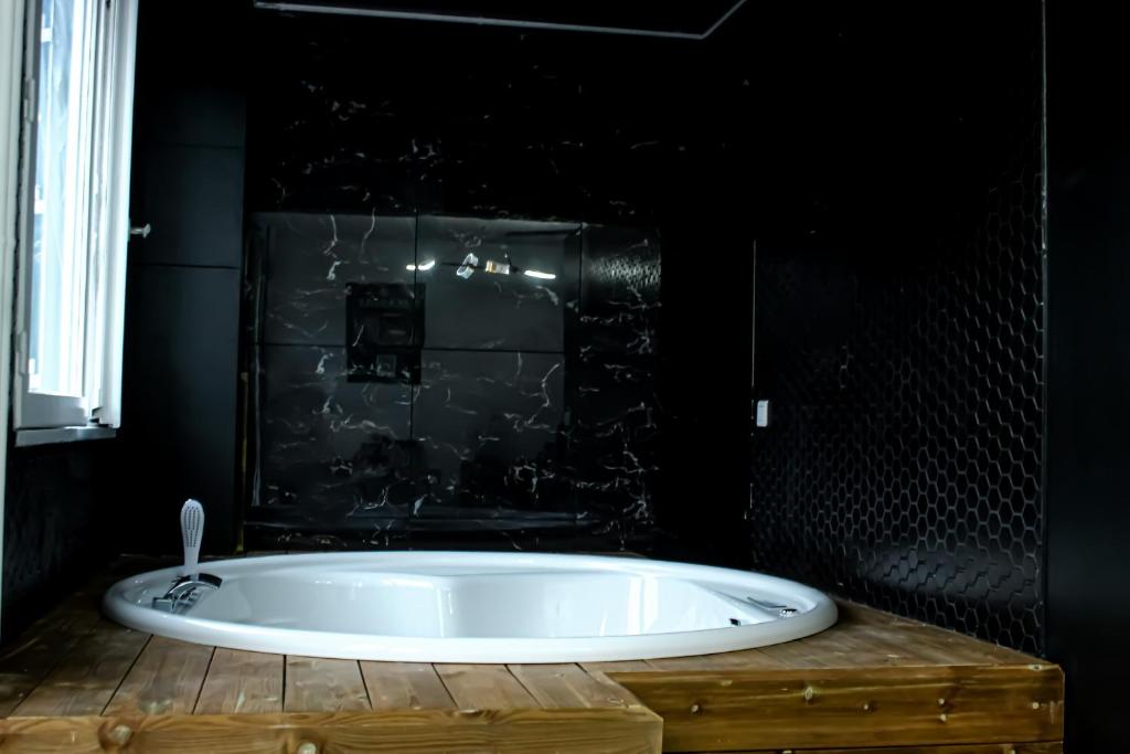 勒布朗-梅尼尔Seasides Paris - Suite Monroe的带浴缸的浴室和黑色墙壁