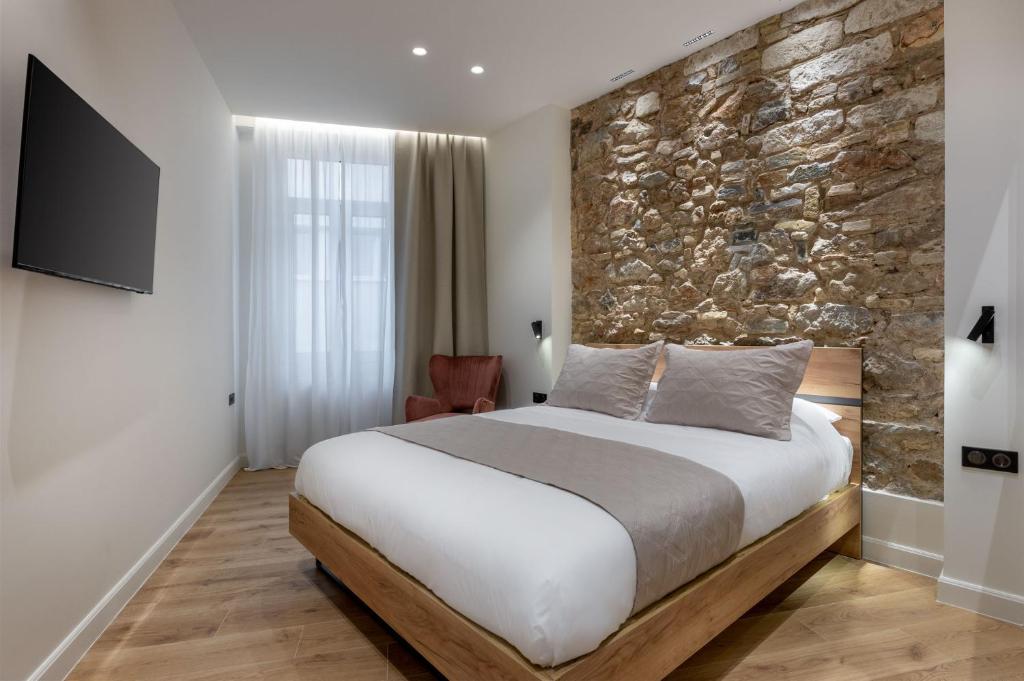 雅典J&A Luxury Residence的一间卧室设有一张大床和石墙