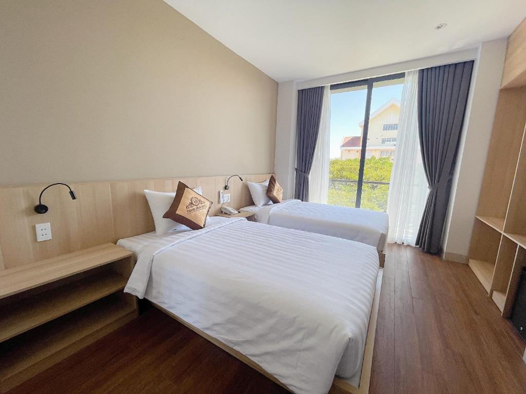 邦美蜀Thanh Bình Hotel - 47 Y Bih - BMT的配有窗户的酒店客房内的两张床