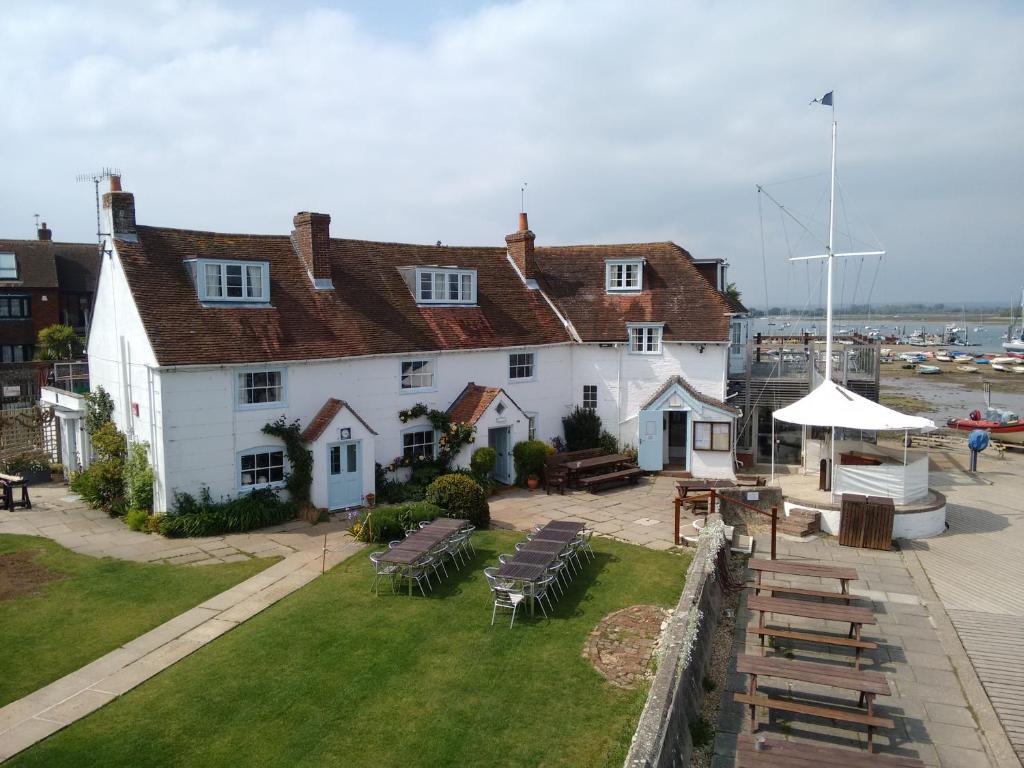 奇切斯特Itchenor Sailing Club的一座带椅子和野餐桌的大型白色建筑