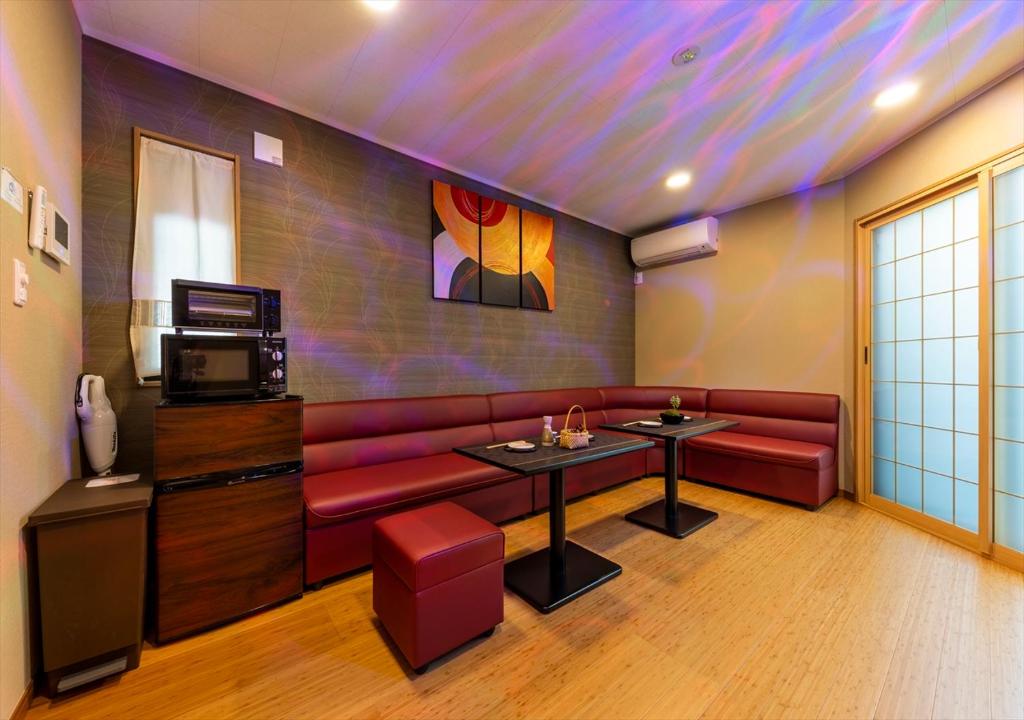东京YADOYA 夢路的客厅配有红色沙发和电视