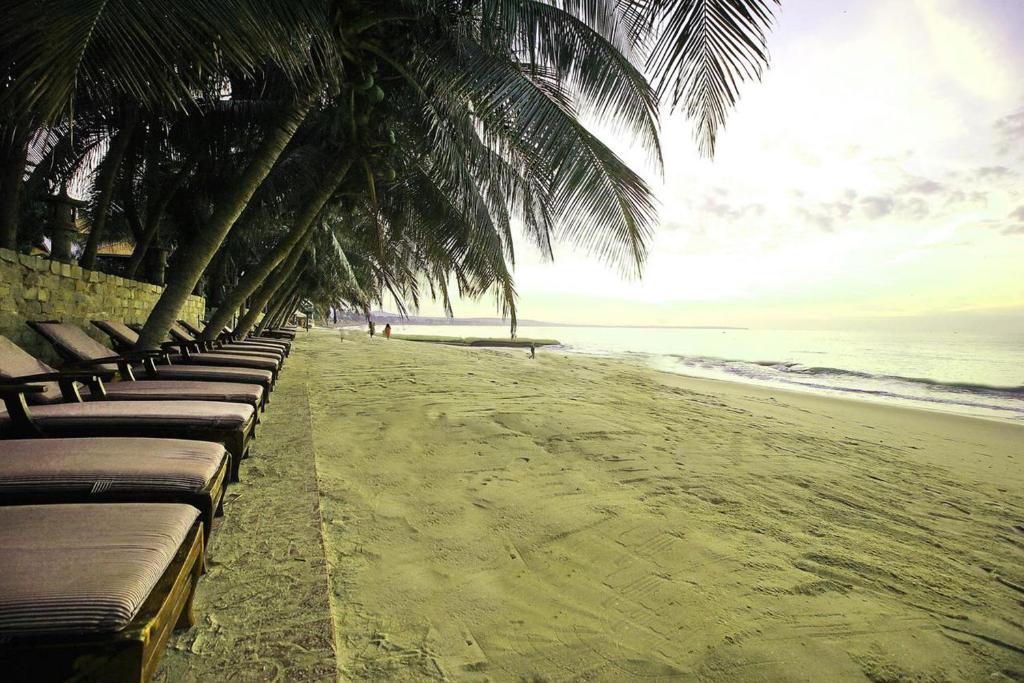 美奈Le Huynh Mui Ne Hotel的海滩上一排躺椅