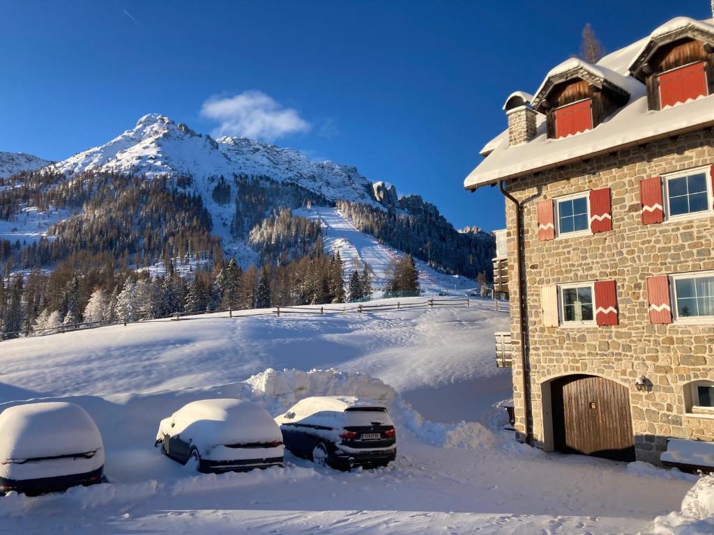 卡雷扎湖Renoviertes Apartment mit Terrasse an der Piste mit kostenlosen WiFi的两辆汽车停在大楼旁边的雪地里