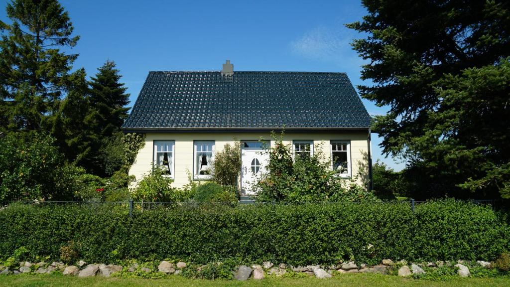 SchaalbyMaries Haus的黑屋顶的白色房子,位于树 ⁇ 后面