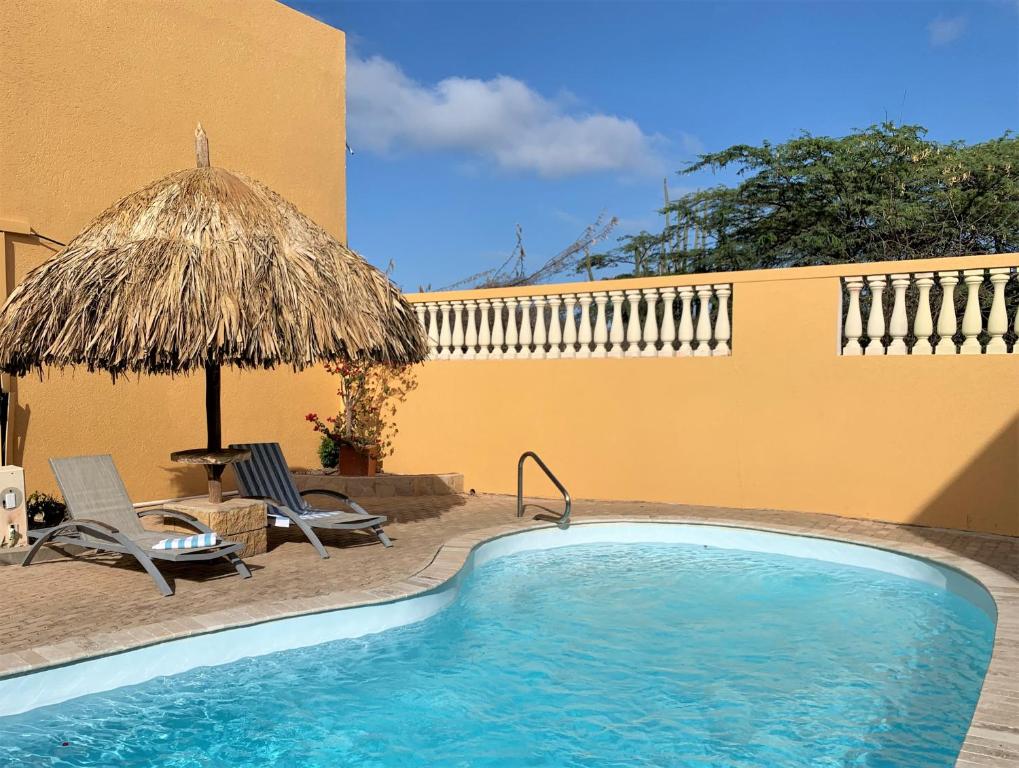 奥拉涅斯塔德Montana Eco Resort Aruba的一个带遮阳伞和椅子及桌子的游泳池
