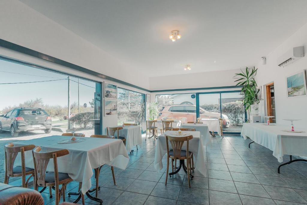 埃斯特角城Apart Hotel Punta Azul的餐厅设有白色的桌椅和窗户。