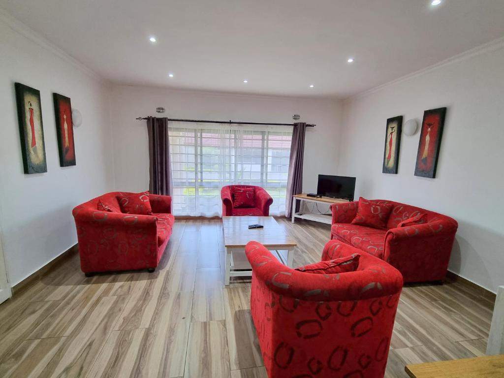 恩多拉Mwaiseni Maisonettes apartments的客厅配有2把红色椅子和桌子
