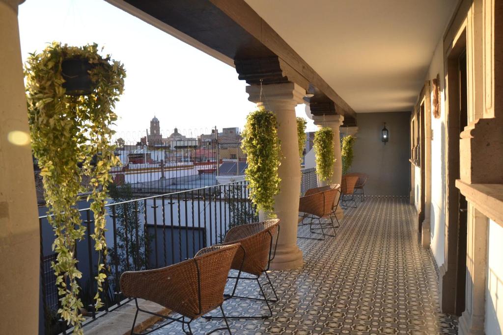 克雷塔罗Hotel Boutique Casa Loreta的大楼内的阳台配有椅子和植物