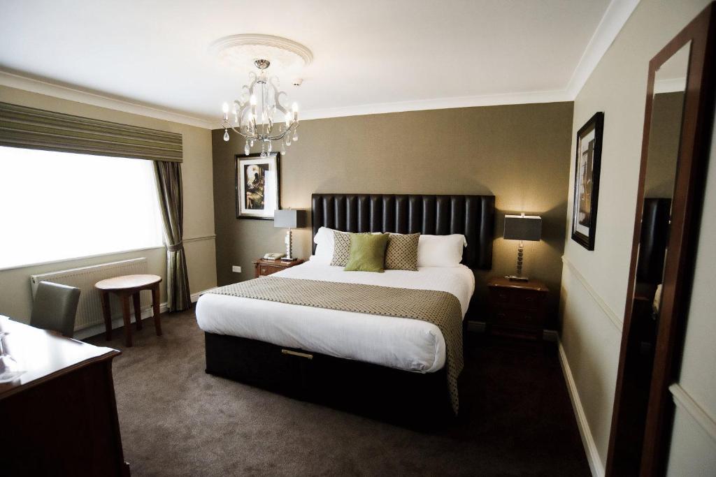 北基林格霍梅阿什伯恩宾馆的一间卧室配有一张大床和一个吊灯。