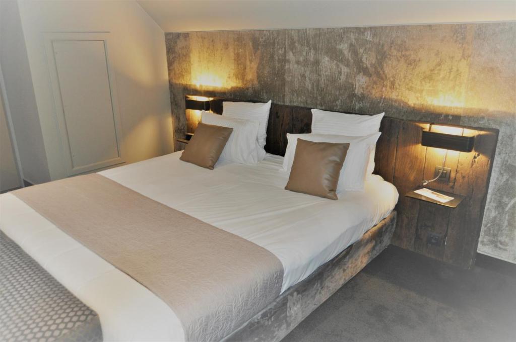 Péruwelz圣丹尼尔酒店的卧室配有一张带白色床单和枕头的大床。