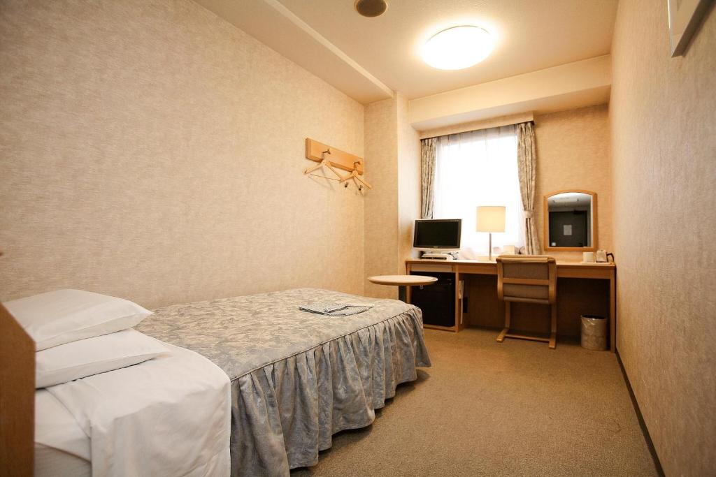 成田成田U-城市酒店的客房设有一张床、一张桌子和一台电脑