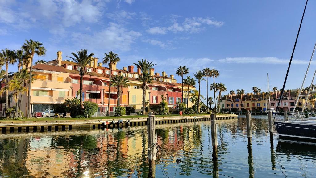 索托格兰德Luxury Penhouse, Sotogrande Marina - Located in an exclusive island of the Marina的一条水体中的船,有建筑和棕榈树