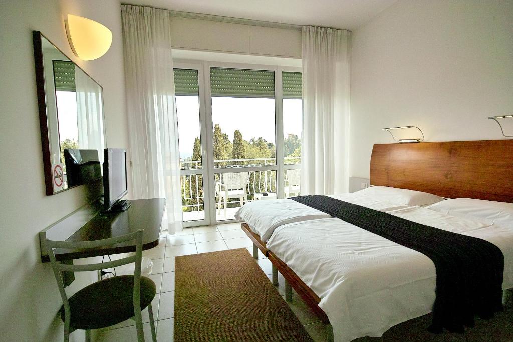 拉帕洛阿普罗多酒店的一间带一张床和一张书桌的卧室以及一个阳台