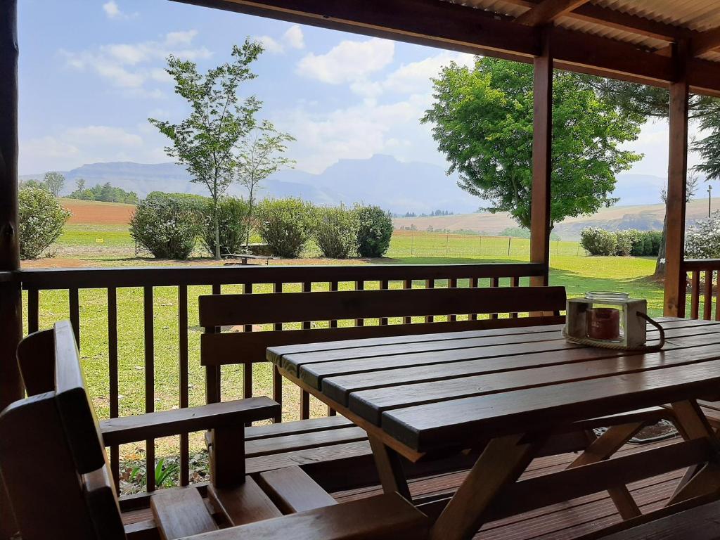 温特顿Mountain Splendour Eco Resort的门廊上的木桌,享有田野的景色