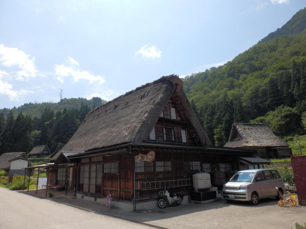 南砺果约蒙民宿 的一座带茅草屋顶的建筑,前面设有停车场