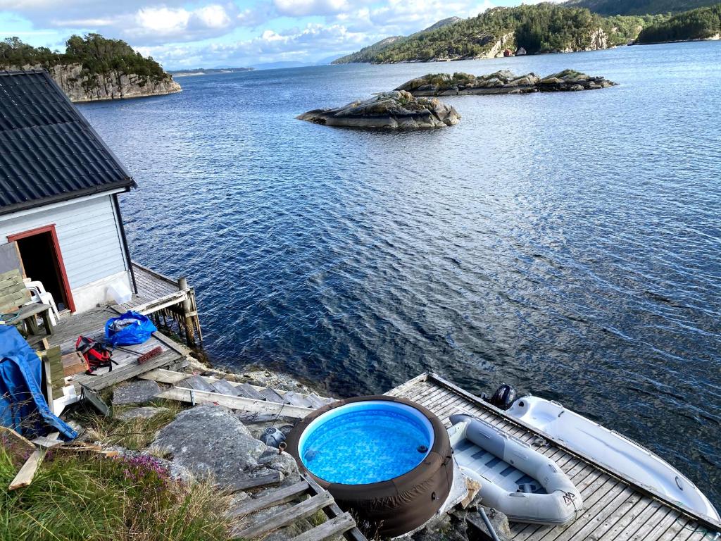 HaganesBergen/Sotra: Sea cabin. Spa. Fishing. Boat的船在水面上房子旁边的码头上