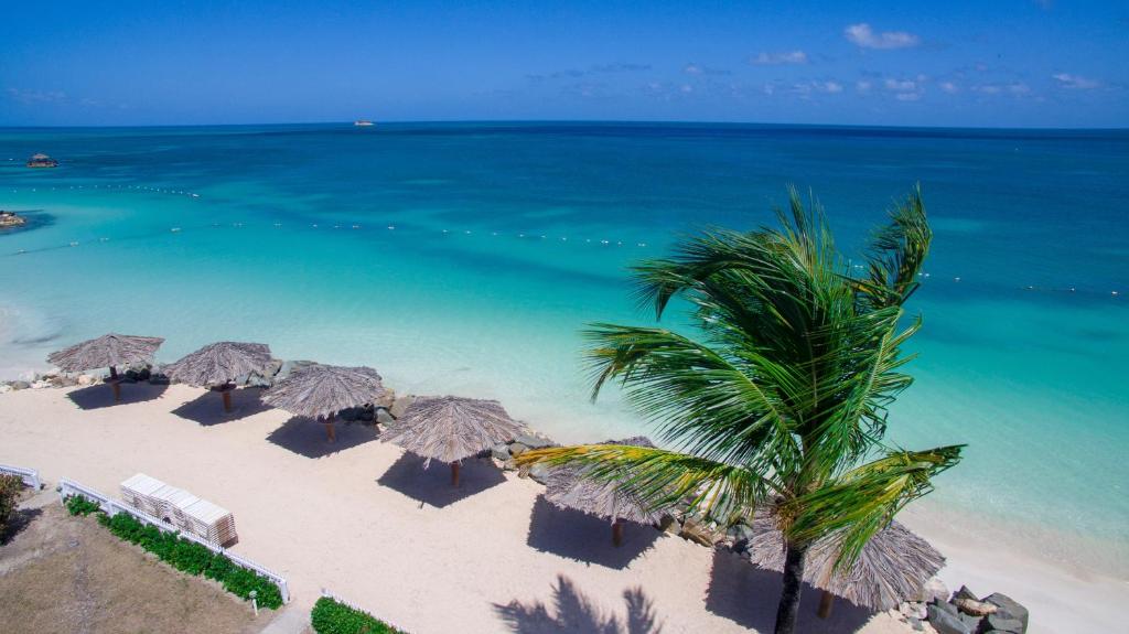 圣约翰斯Dickenson Bay Oasis at Antigua Village的享有海滩的空中景致,配有遮阳伞和海洋