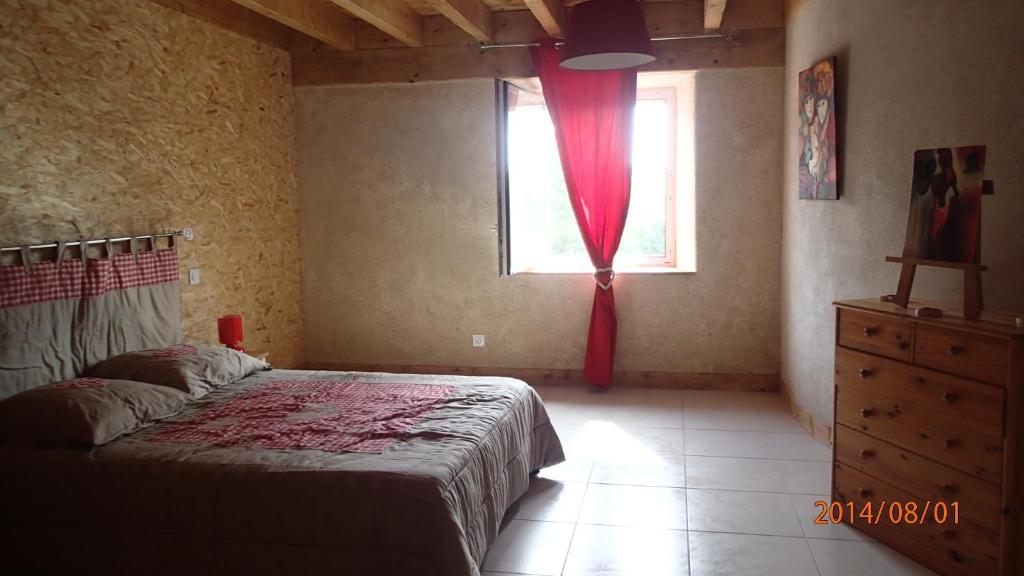 Saint-André-de-Chalençon燕子巢度假屋的一间卧室配有一张床和一个带红色窗帘的窗户