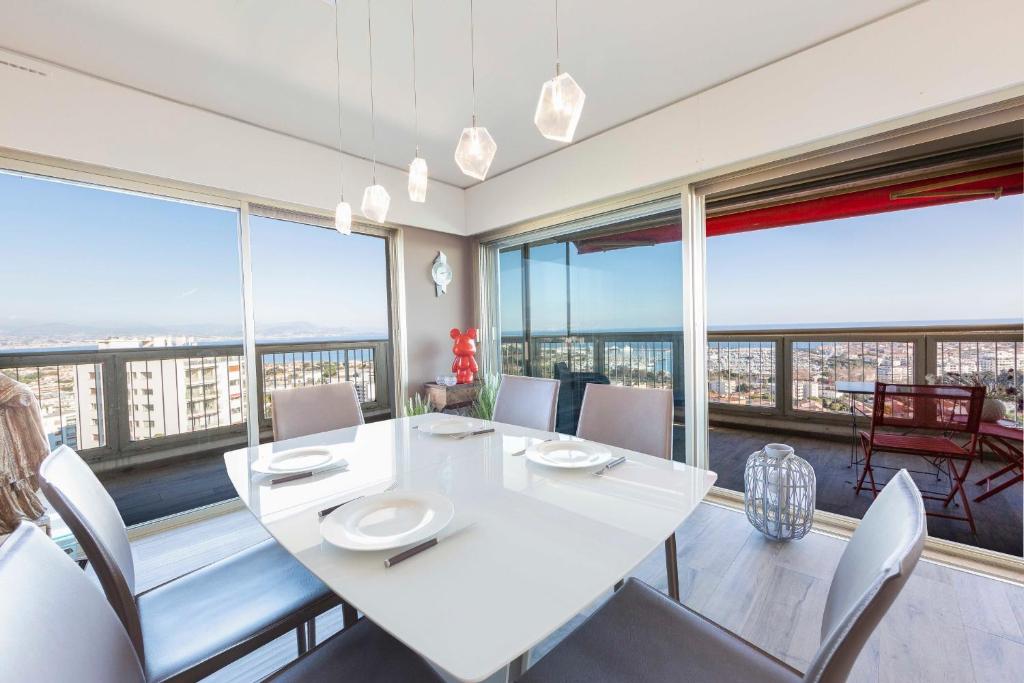昂蒂布BNB RENTING breathtaking view 2 bedroom apartment in Antibes !的一间设有白色桌椅和大窗户的用餐室