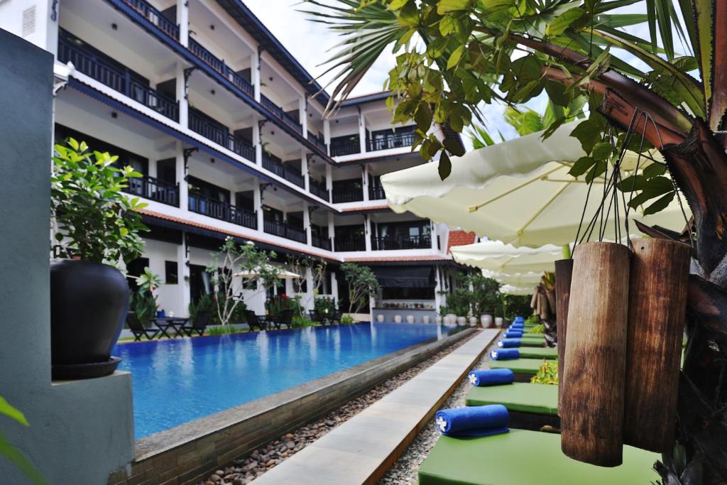 暹粒高棉公馆精品酒店的酒店游泳池设有躺椅和遮阳伞