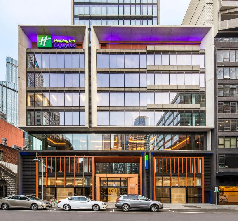 墨尔本Holiday Inn Express Melbourne Little Collins, an IHG Hotel的前面有汽车停放的建筑