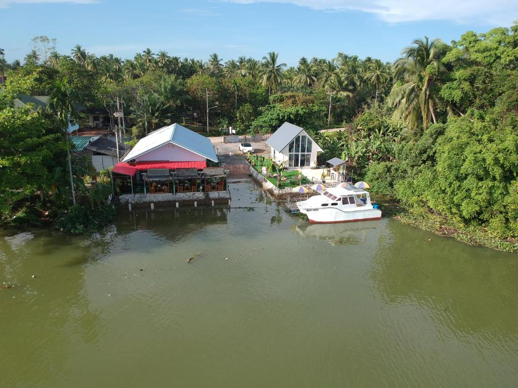 素叻Boat house marina restaraunt and homestay的船停靠在河边的房子旁边