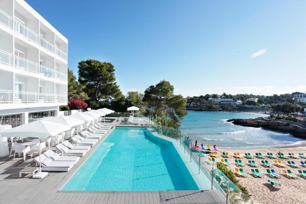 波蒂纳茨Grupotel Ibiza Beach Resort - Adults Only的一个带躺椅的游泳池和一间酒店