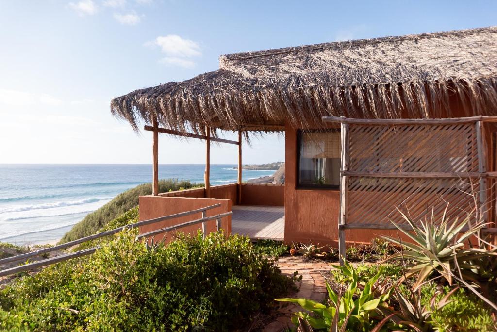 伊尼扬巴内Bela Flor Beach Front Apartments的茅草屋顶和大海的海滨别墅