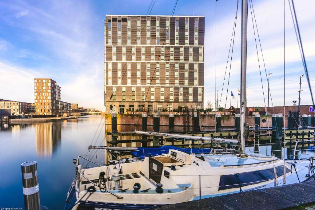 阿姆斯特丹Four Elements Hotel的船停靠在码头上,有一座高大的建筑