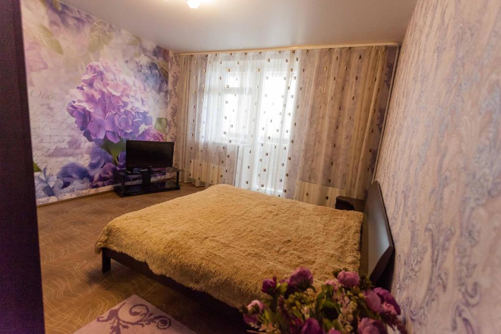 秋明Apartment on Gazovikov 41的一间卧室设有一张床和一个鲜花窗口