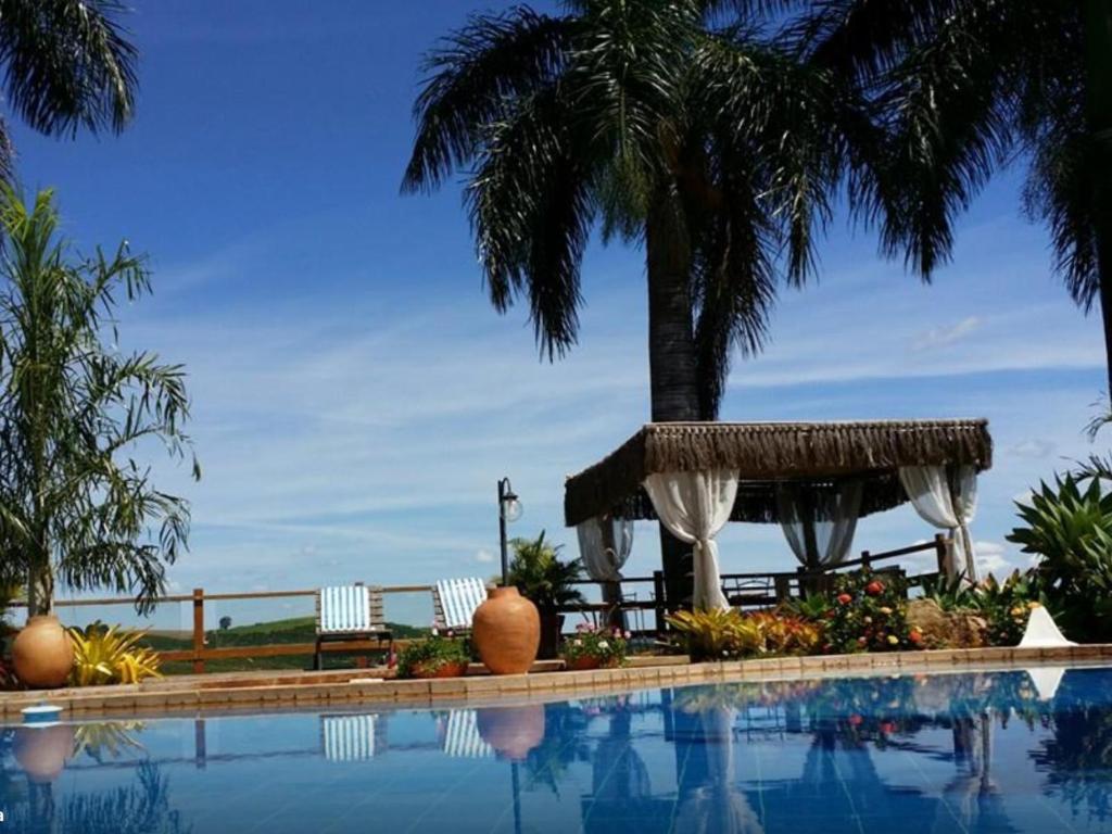 雅库廷加Pousada e Restaurante Caminhos do Bom Café的一座棕榈树环绕的游泳池