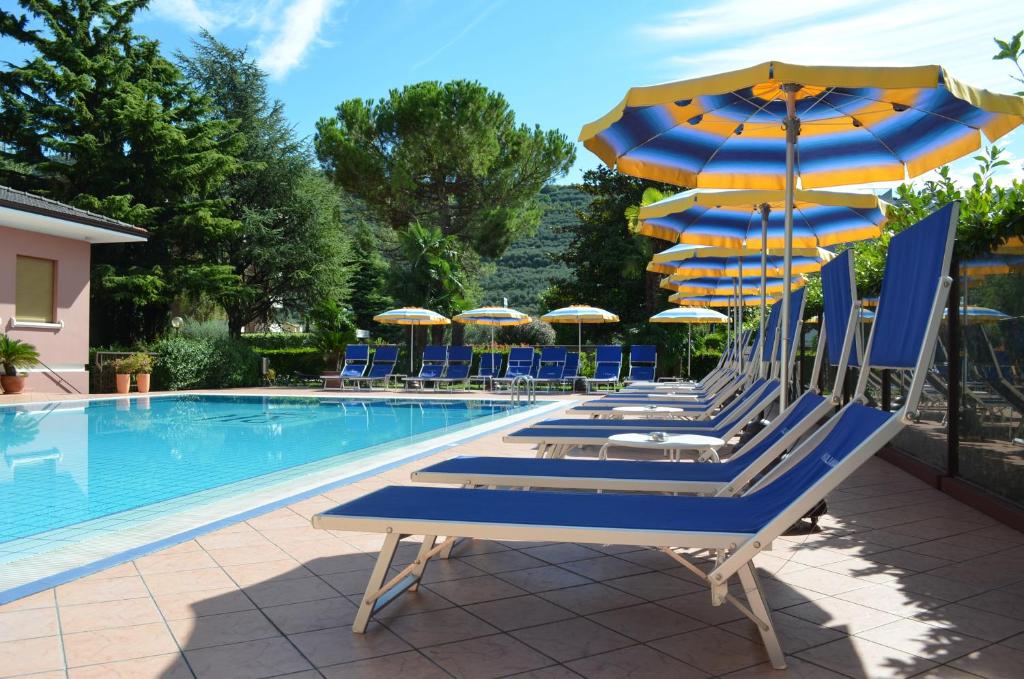 加尔达湖滨SunLake Hotel的一组椅子和遮阳伞,位于游泳池旁