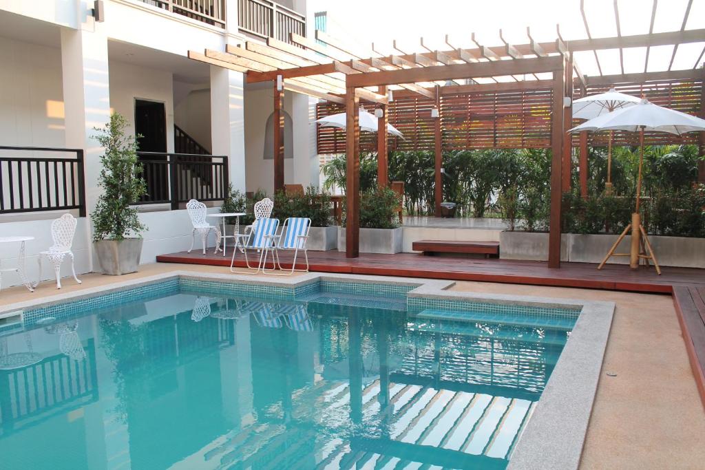 清莱温灿迪酒店的一个带椅子和遮阳伞的游泳池