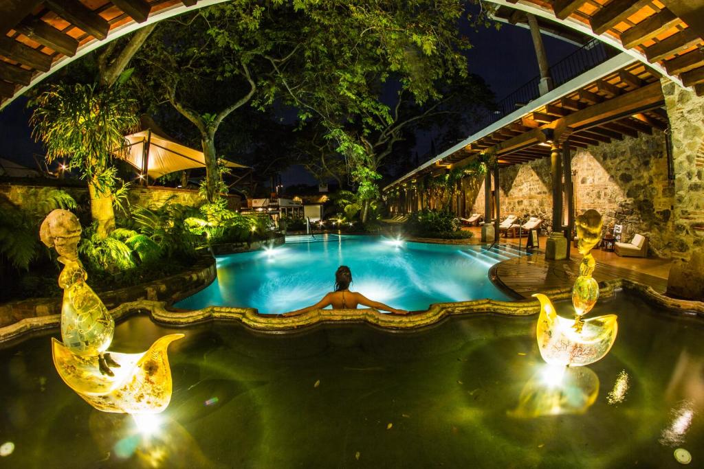 危地马拉安地瓜Hotel Museo Spa Casa Santo Domingo的男人在晚上躺在游泳池里