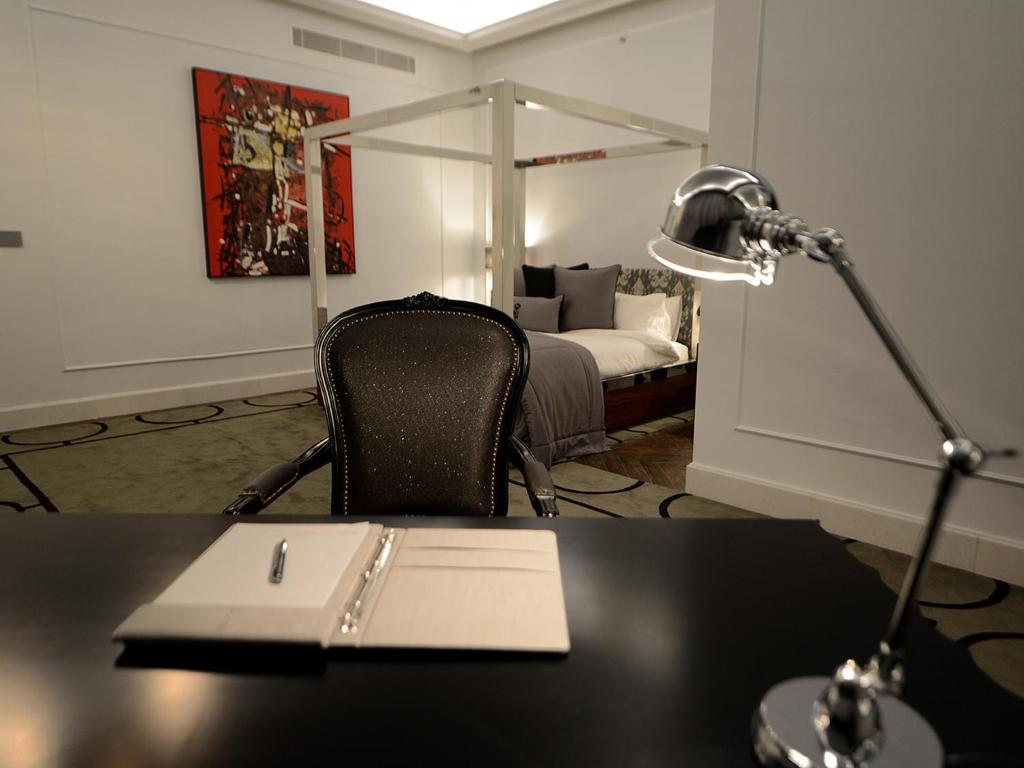 拉合尔尼沙特酒店的一张带台灯的桌子和一张带床的桌子