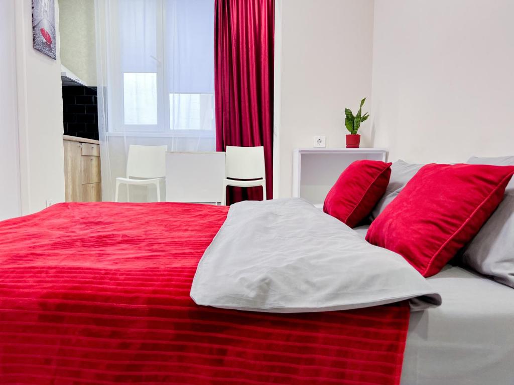 哈尔科夫Новая студия Вокзал Харьков-Пассажирский的红色和白色的床,上面有红色枕头