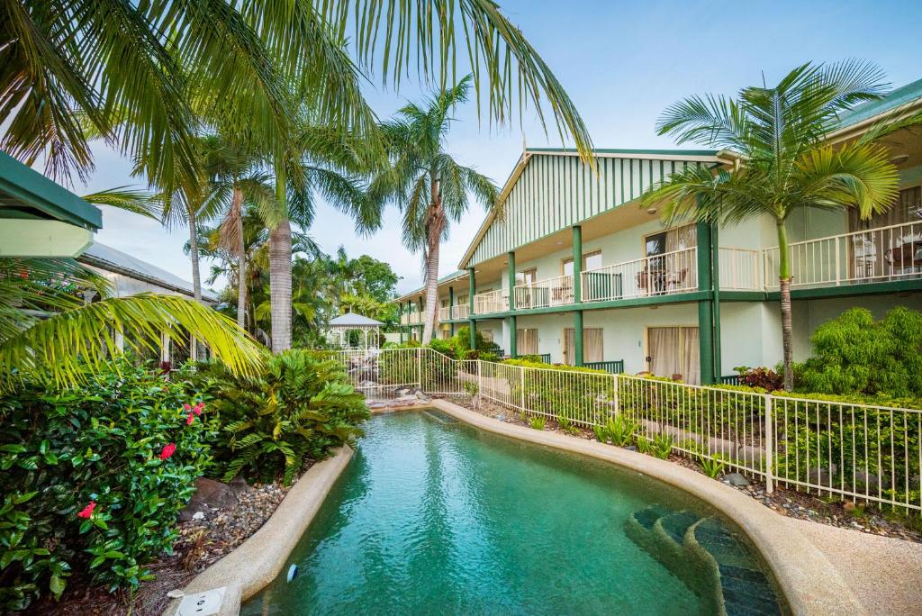 麦凯新乐花园汽车旅馆的棕榈树建筑前的游泳池