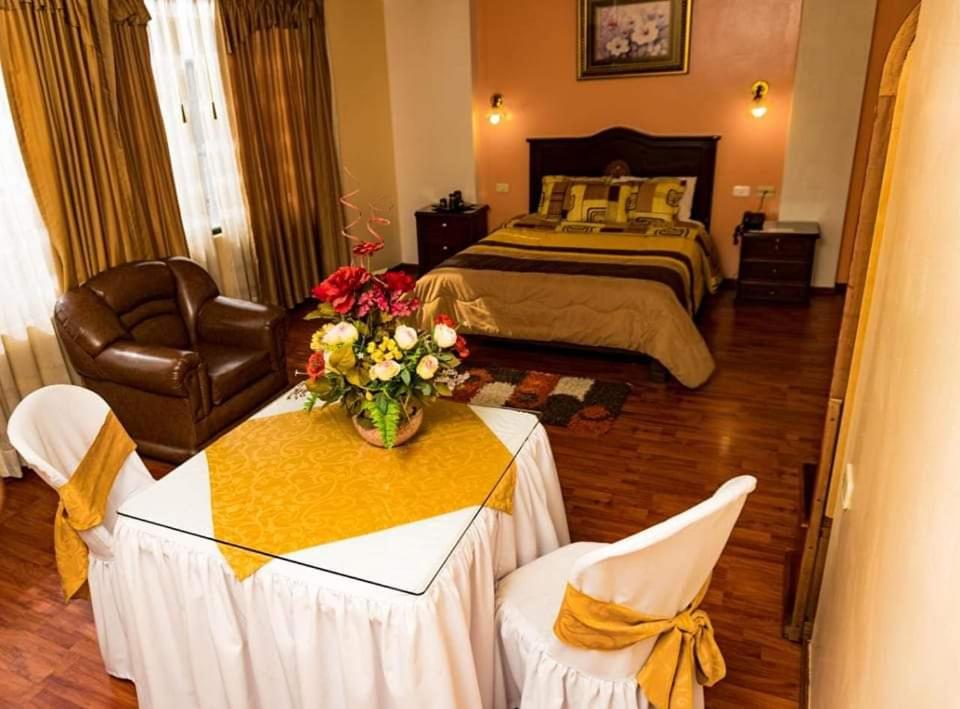 拉塔昆加Hotel Los Ilinizas的一间卧室配有一张床和一张鲜花桌子