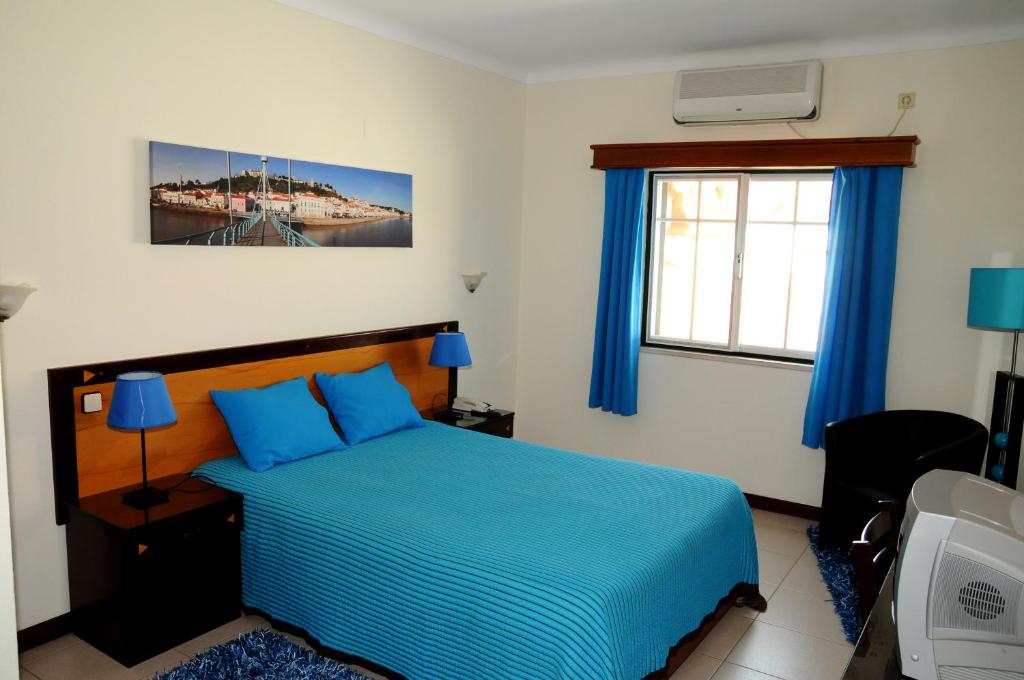 萨尔堡Hotel A Cegonha的一间卧室设有蓝色的床和窗户。